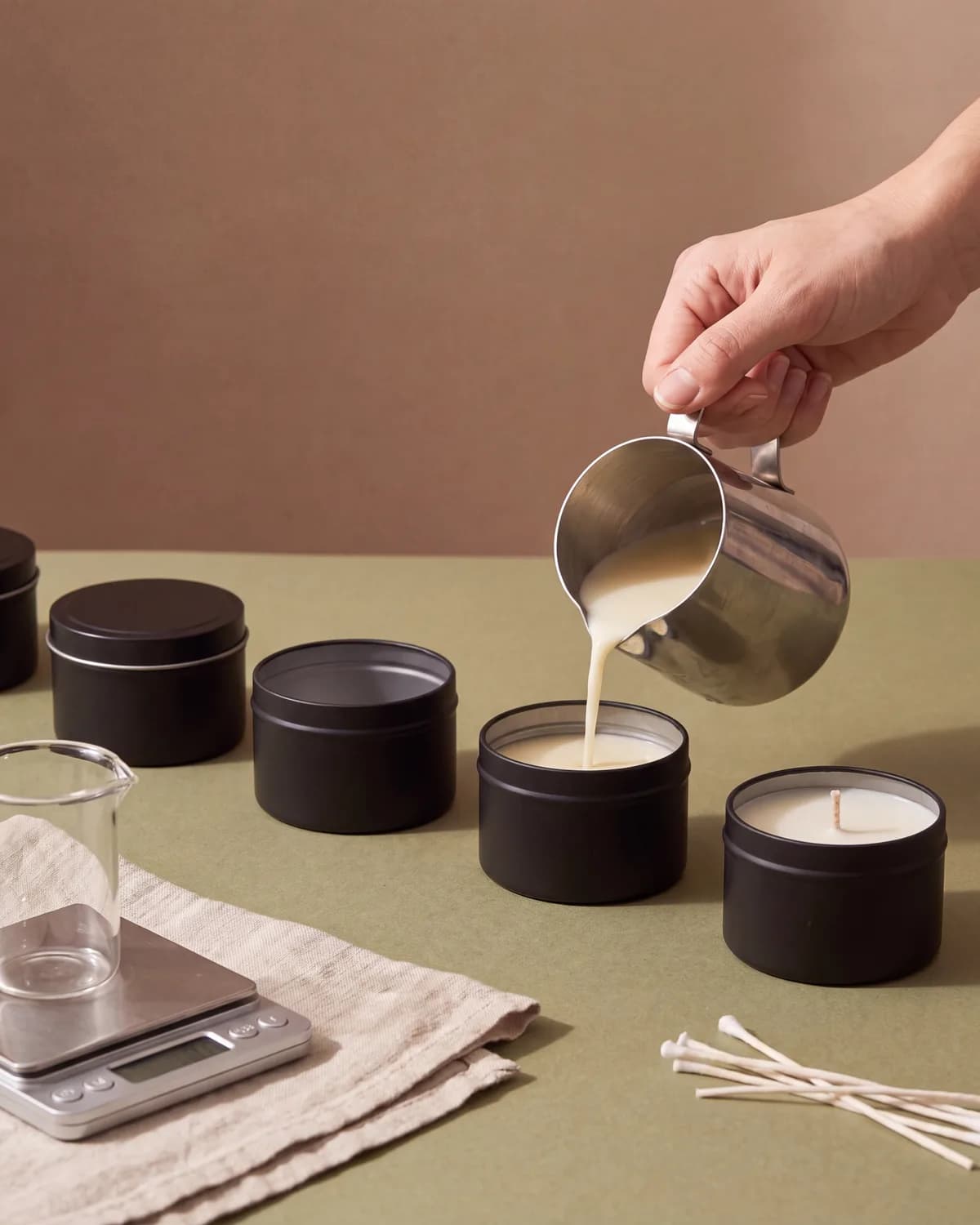 A candle being poured by hand at the Maya studio bench